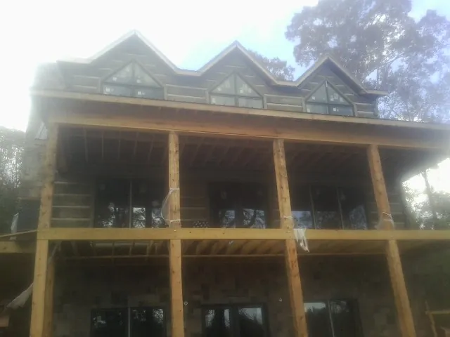 Dormers and porch framing on a large log home under construction — Roof Coating work by our crew in Beaman