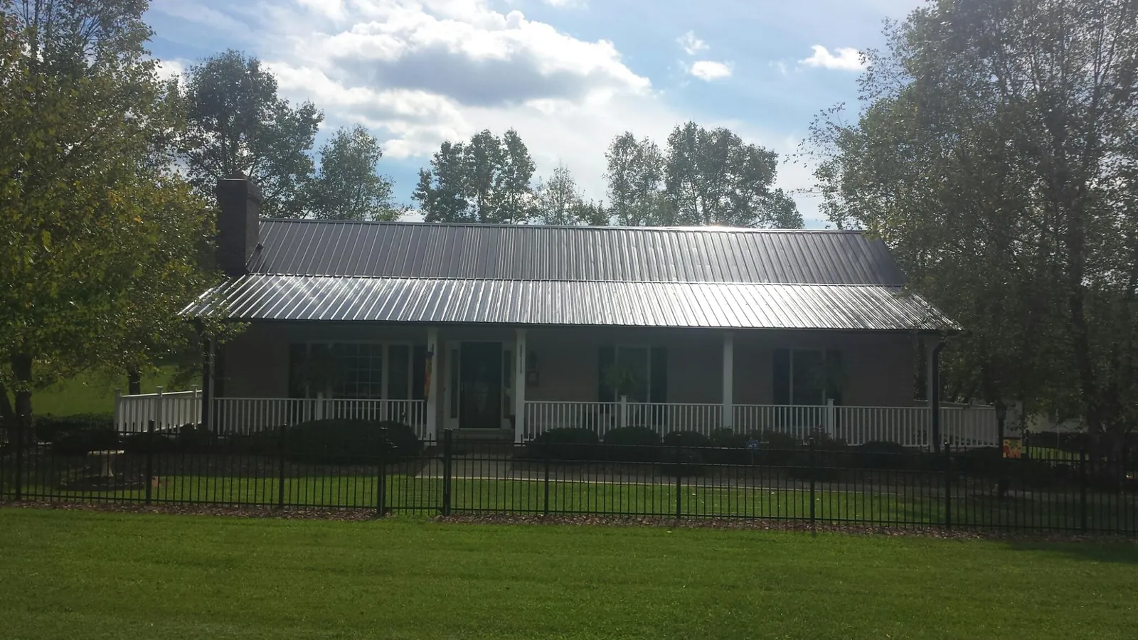 Gray metal roof on a brick ranch with a full width front porch — Gutter Guard Installation work by our crew in Beaman