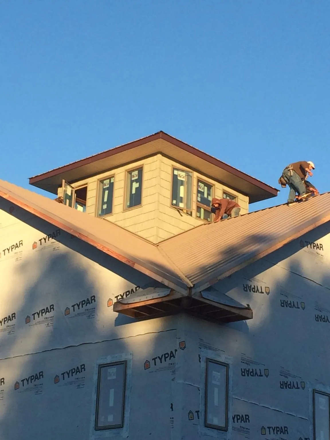 Roofers working around a rooftop cupola on a new metal roof at sunset — Roof Waterproofing in Beaman by Roofing Brothers